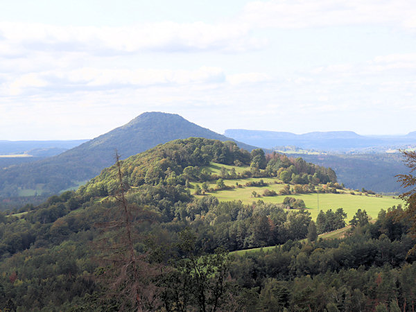 Blick auf den Větrný vrch von Osten. Dahinter liegt der Růžovský vrch (Rosenberg) und im Hintergrund rechts der massive Tafelberg Großer Zschirnstein.