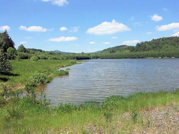 Pohled z hráze na Horní Kunratický rybník. V pozadí je hora Luž.