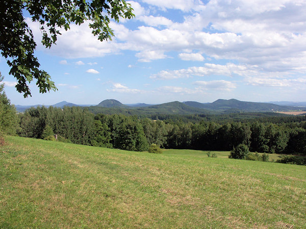 Výhled z dolního okraje lesa k jihovýchodu na Ortel a další kopce v okolí Sloupu.